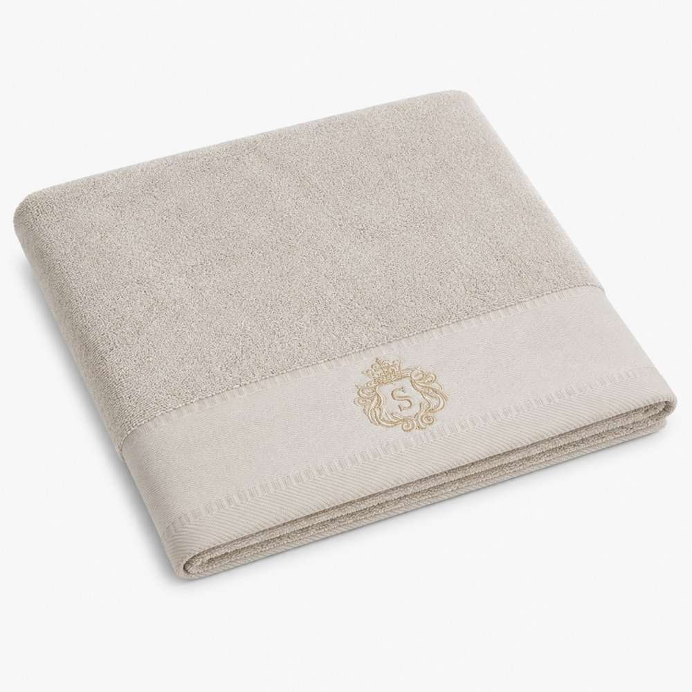 Serviette de bain beige en éponge épaisse, brodée d’un blason ton champagne